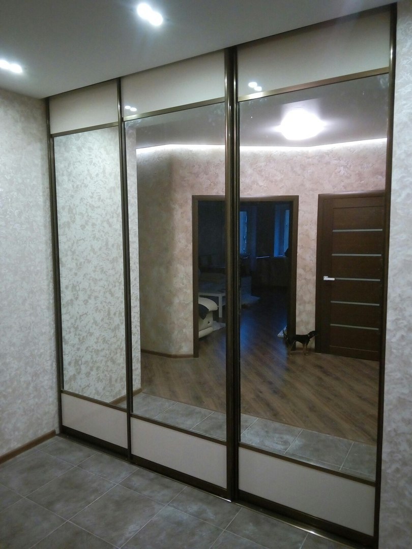 Зеркальные двери шкафа изготовлены с небольшими вставками внизу и вверху