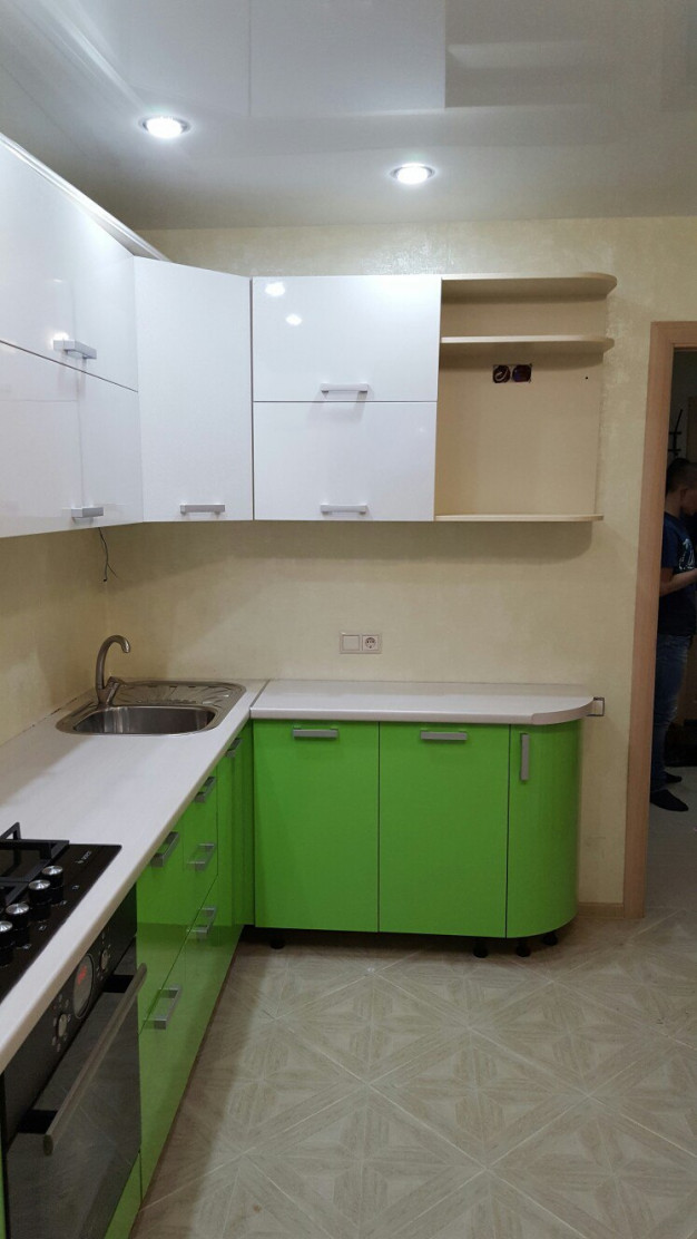 Зелёная угловая кухня с радиусными фасадом и белым верхом