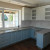 Голубая п-образная кухня с белым верхом и фигурными дверями