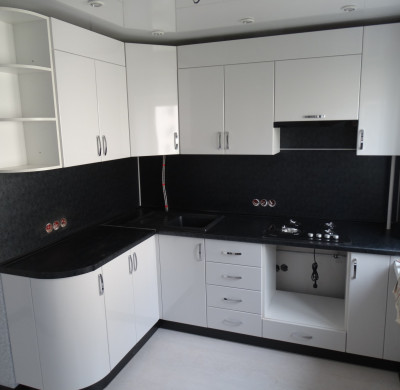 Белая угловая кухня с радиусным фасадом и черной столешницей