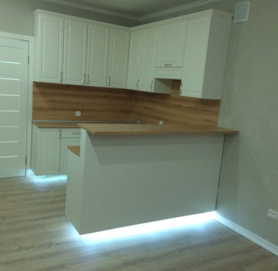Белый подвесной кухонный гарнитур с подсветкой и барной стойкой