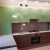 Коричневая угловая кухня с зелёными навесными шкафами